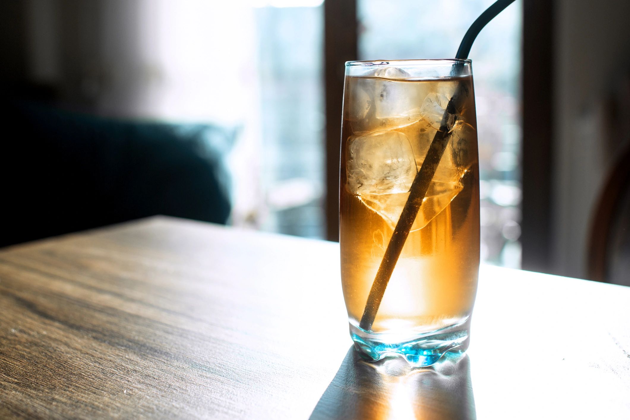 Iced drink in a glass with ice cubes and a metal straw